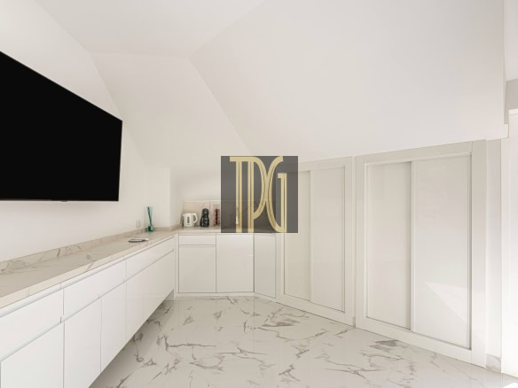 White minimalist kitchen with marble countertops and floors, large wall-mounted TV, and a glass door to the outdoor balcony, high ceilings.