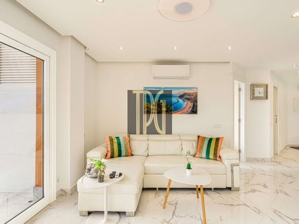 Bright living room with a white sectional sofa, colorful striped cushions, and a marble floor near a sliding glass door to a balcony.