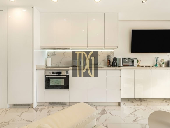 White contemporary kitchen with glossy cabinets, marble backsplash, and built-in oven under a stovetop.