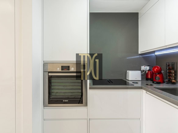 Modern white kitchen with a built-in Bosch oven, induction cooktop, and gray countertop appliances.
