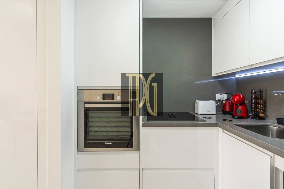 Modern white kitchen with a built-in Bosch oven, induction cooktop, and gray countertop appliances.