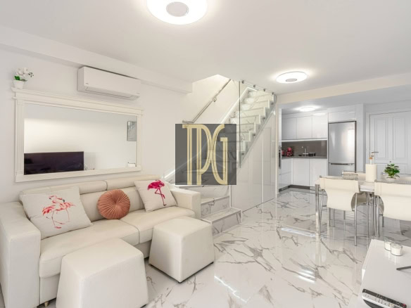 Bright open-concept living area with a white leather sofa, marble floors, glass-railed staircase, and a nearby dining/kitchen space.