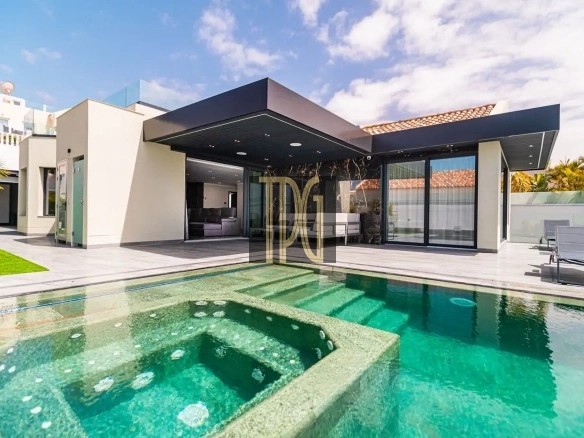 Modern single-story home with glass walls and a large turquoise swimming pool in the backyard, outdoor lounge area visible beneath a dark canopy, sunny sky above.