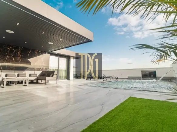 Modern upscale outdoor living area with marble patio, white cushioned seating, and a rectangular pool with lounge chairs under a covered patio, blue sky overhead and palm leaves in the foreground