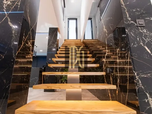 Modern open-riser wooden staircase framed by glossy black marble walls in a luxury interior
