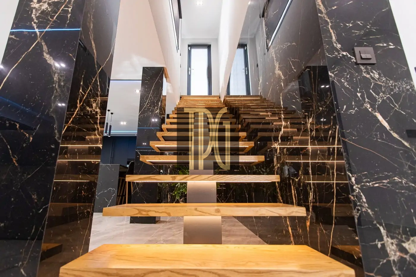 Modern open-riser wooden staircase framed by glossy black marble walls in a luxury interior