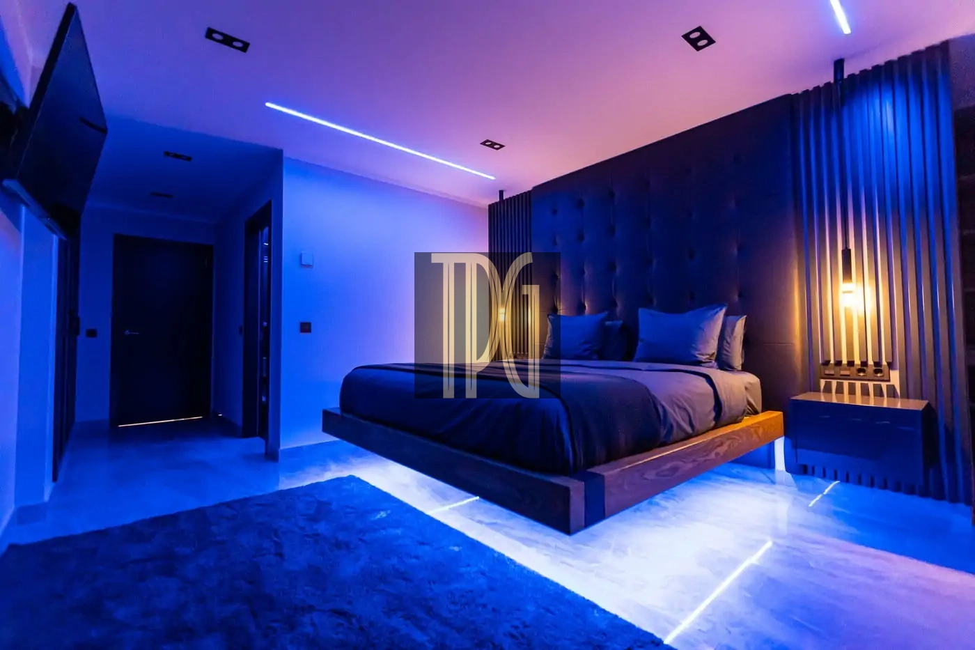Luxurious bedroom with a low platform bed, dark upholstered headboard, blue ambient lighting and a glowing floor strip