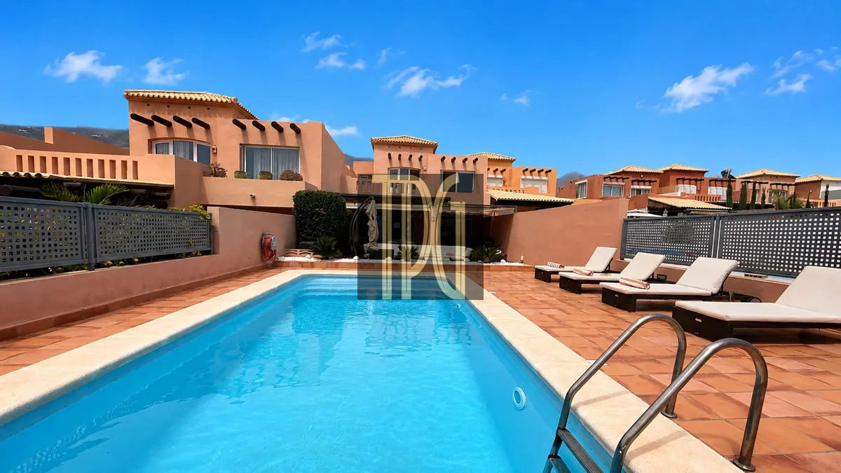 File 00008jpg Outdoor swimming pool with terracotta patio and sun loungers on the deck under a bright blue sky at a resort.