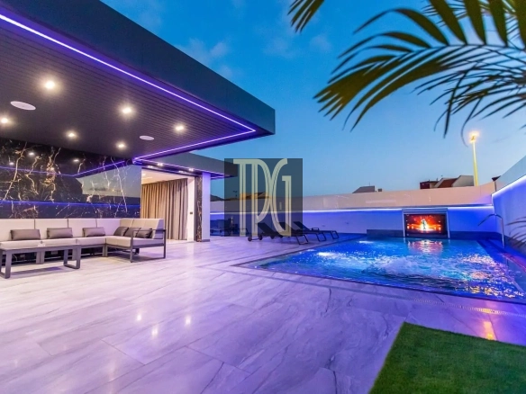 Luxurious rooftop terrace at dusk with purple LED lighting, beige sectional seating, and a rectangular pool with a wall-mounted screen.