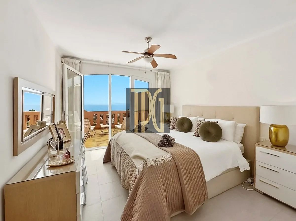 File 00016jpg Bright, modern bedroom with a king bed, beige headboard, and brown throws, opening to a sunny ocean-view balcony.
