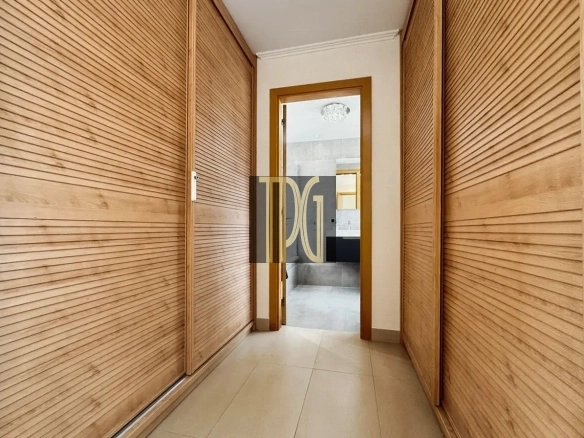 Narrow hallway with wooden louvered closet doors on both sides, opening to a bathroom at the end.