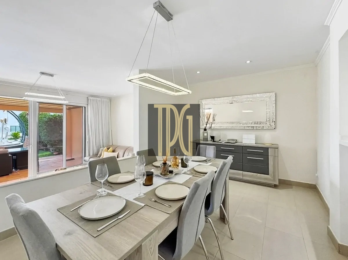 File 00022jpg Contemporary dining room with a long wooden table set for eight, grey chairs, pendant light, and a sideboard with a mirrored wall panel.