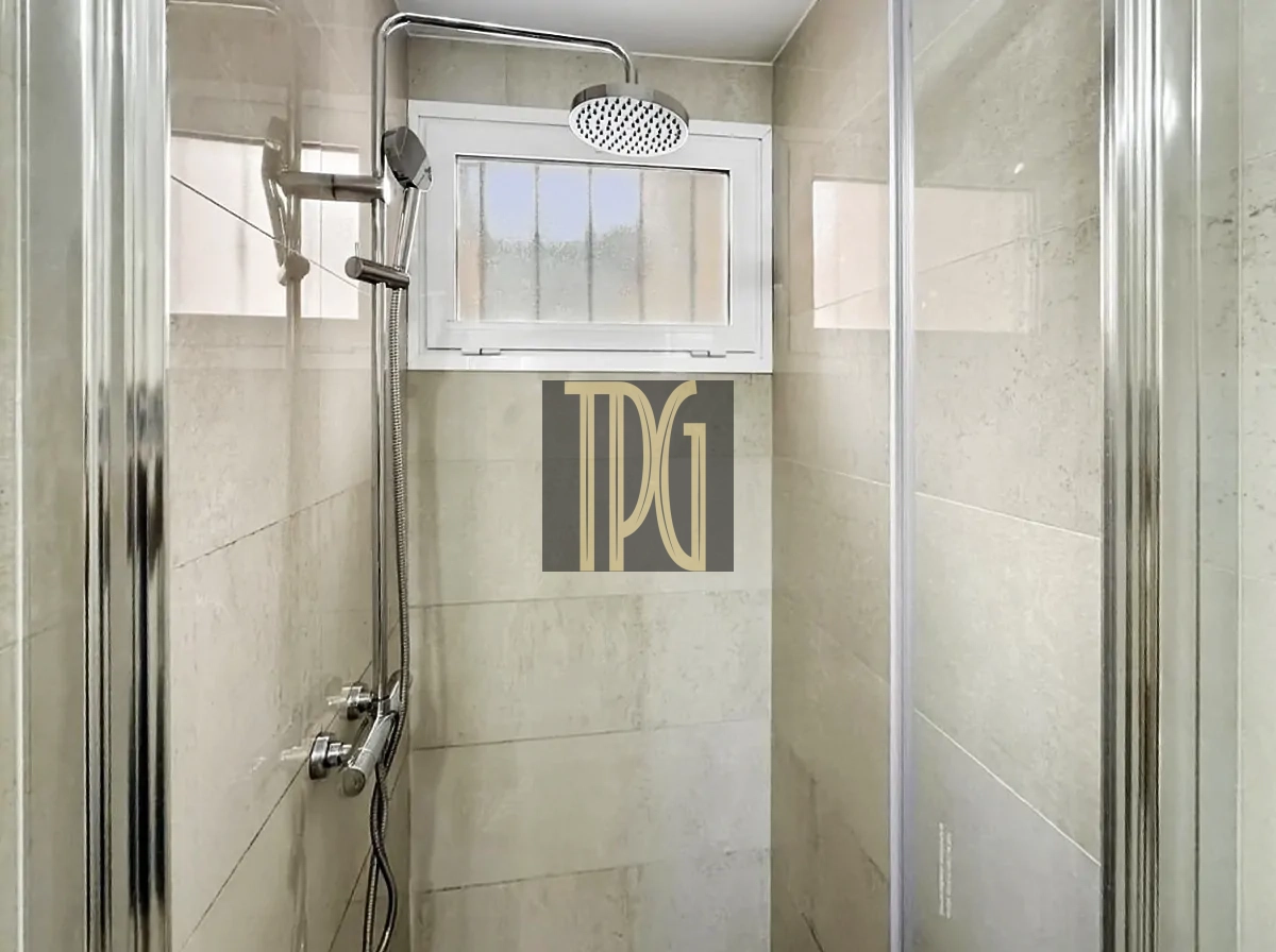 File 00023jpg Modern glass-enclosed shower with a ceiling rainfall head, handheld wand, and tiled beige walls, plus a small window above.
