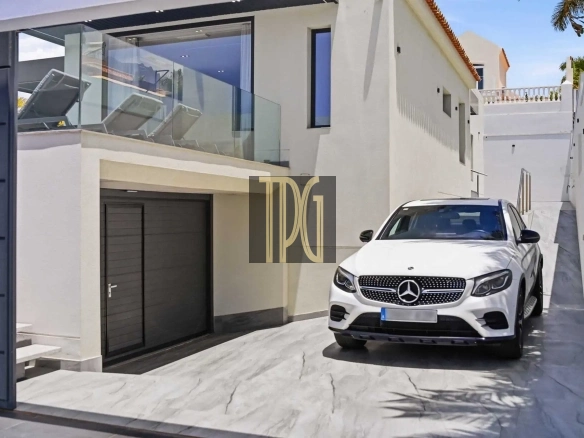 White Mercedes SUV parked on a marble driveway in front of a modern white two-story house with a glass balcony.