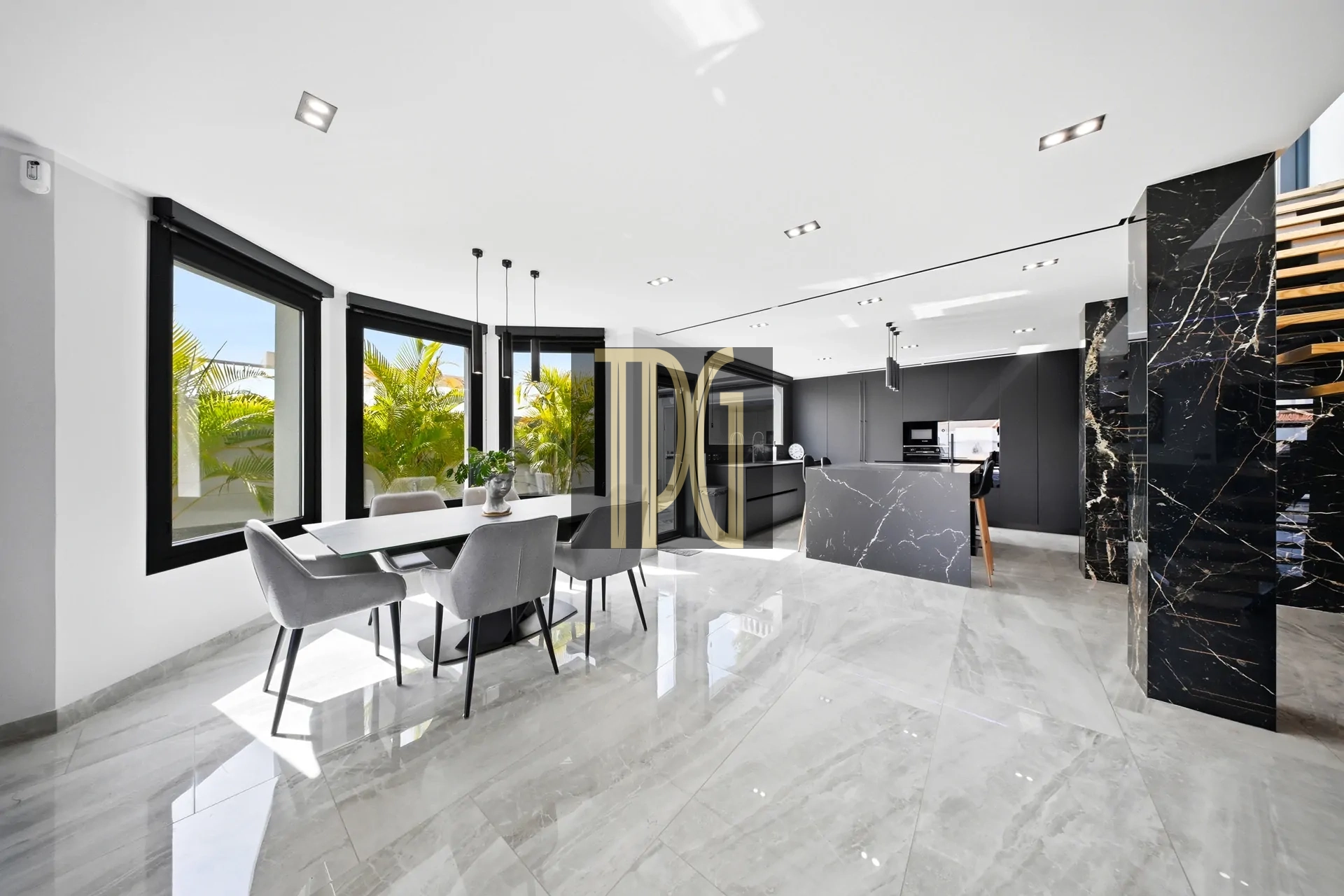 Open-plan kitchen and dining area with marble floors, grey cabinetry, and large windows overlooking greenery outside.