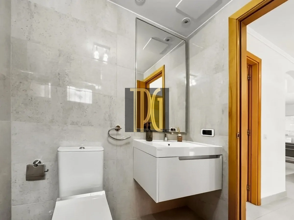 File 00026jpg Modern bathroom with white vanity sink, large mirror, wall-mounted cabinet, and toilet next to a towel ring and toilet paper holder.