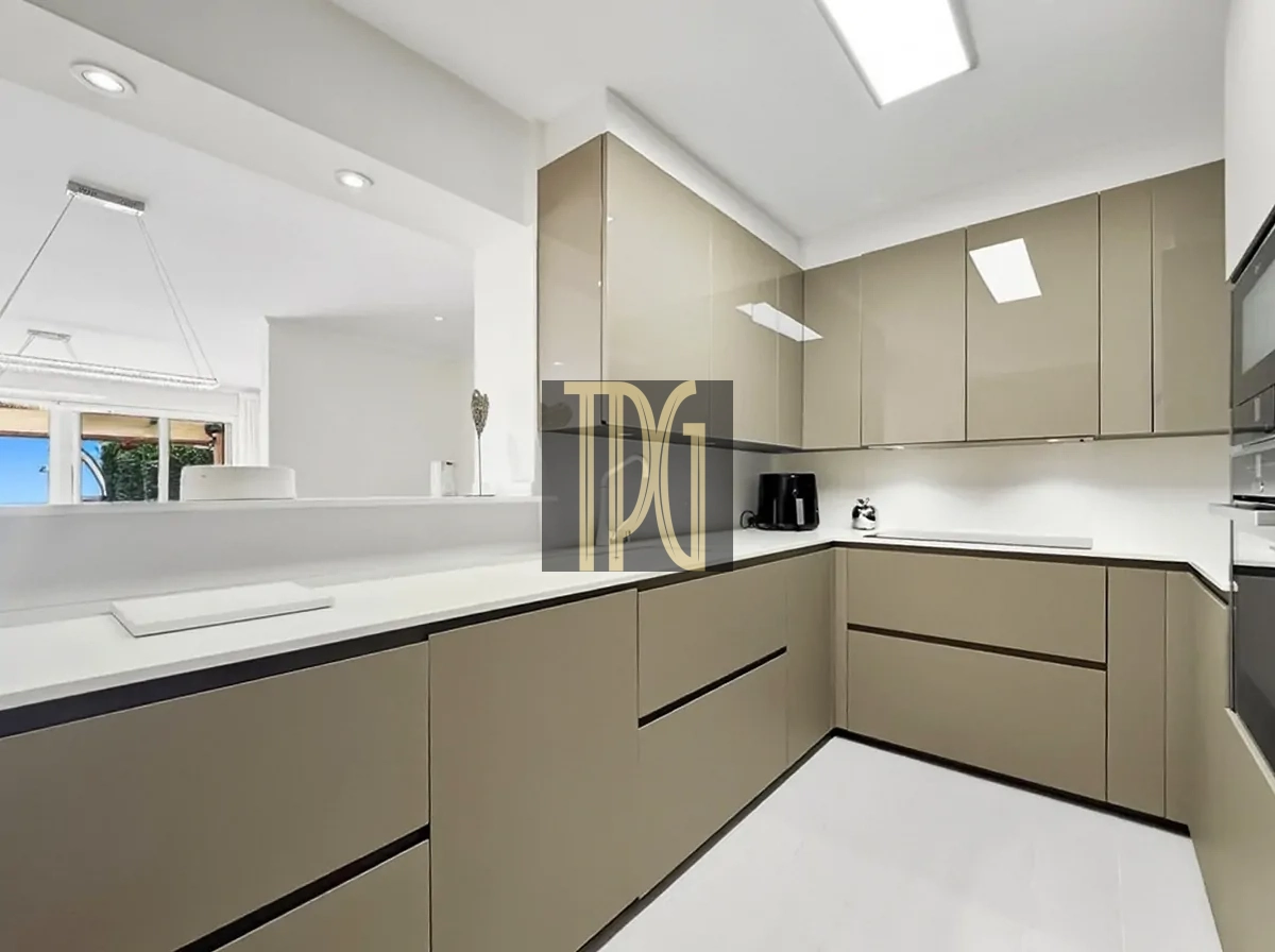 File 00027jpg Modern beige L-shaped kitchen with white countertops and built-in cabinets, clean lines, and bright overhead lighting