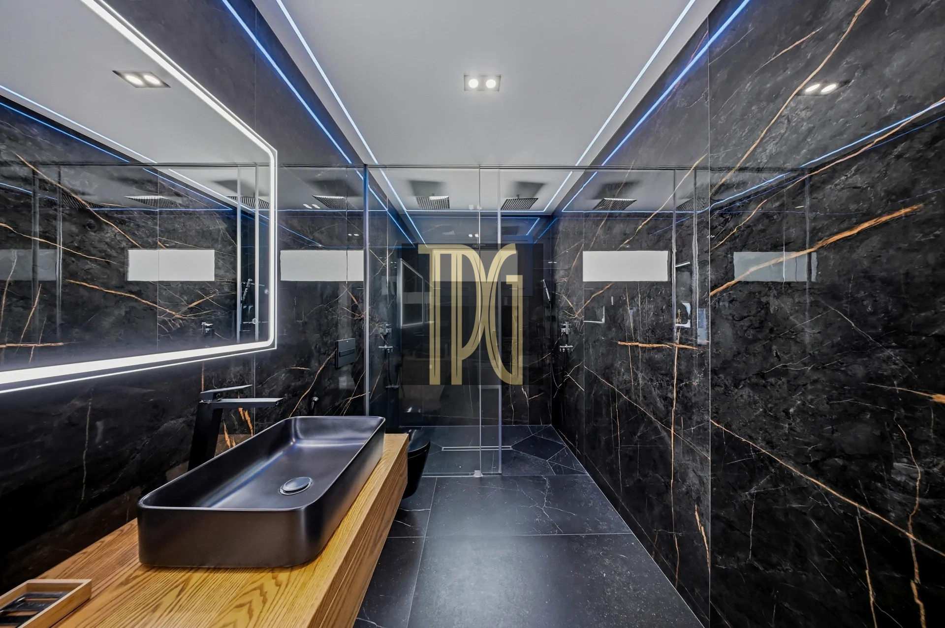 Modern bathroom with black marble walls, glass shower, and a wooden vanity with a black rectangular sink.