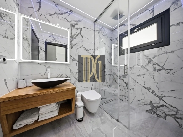 Modern marble bathroom with glass shower, wooden vanity, and backlit mirrors.
