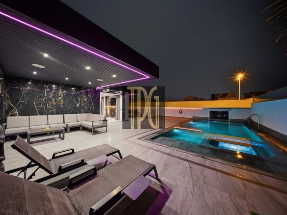 Modern outdoor lounge at night with white sectional seating, marble wall, and purple LED lighting by a illuminated pool.
