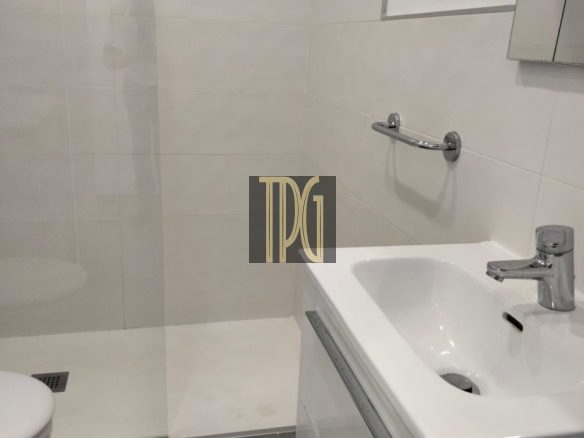 Modern white bathroom with glass shower, wall mirror cabinet, white sink vanity, chrome faucet, and towel rail.”,