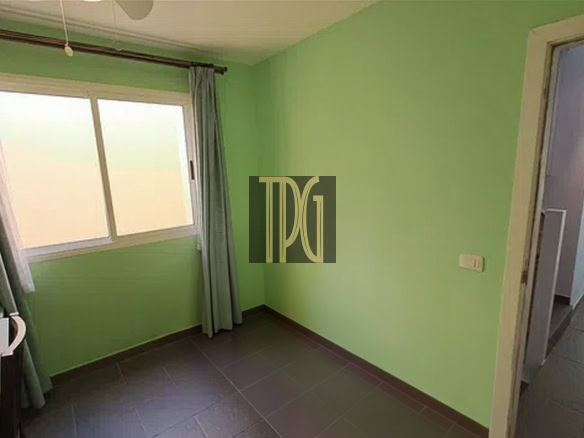 Small empty room with lime green walls, a window with light curtains, and a doorway to a hall.