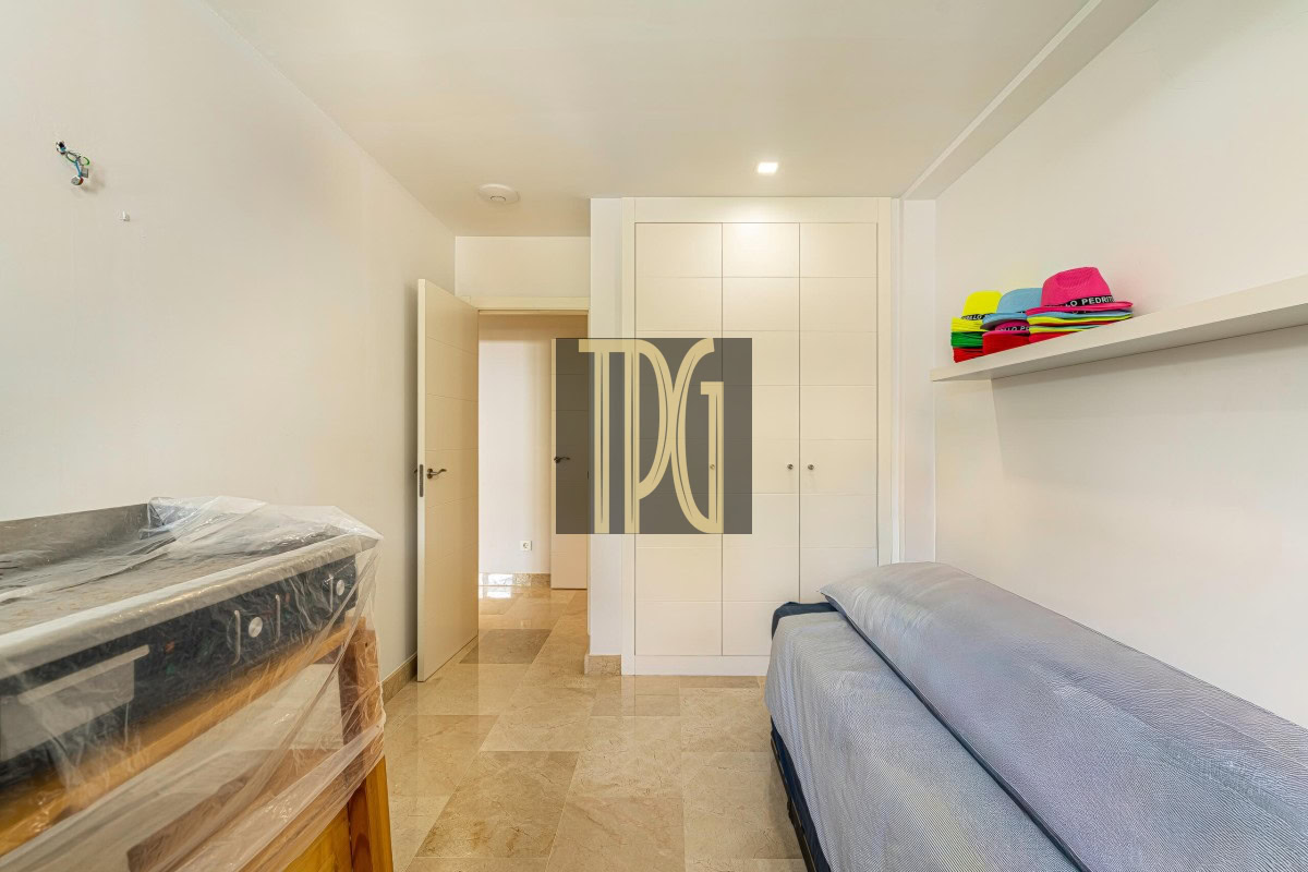 Small white bedroom with a single bed on the right, a white wardrobe, and a shelf of colorful hats on the wall