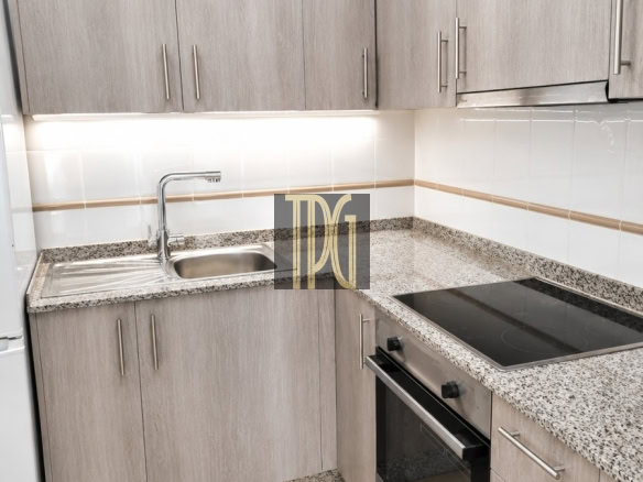 Modern L-shaped kitchen with gray wood cabinets, speckled granite counters, and a stainless sink with faucet.