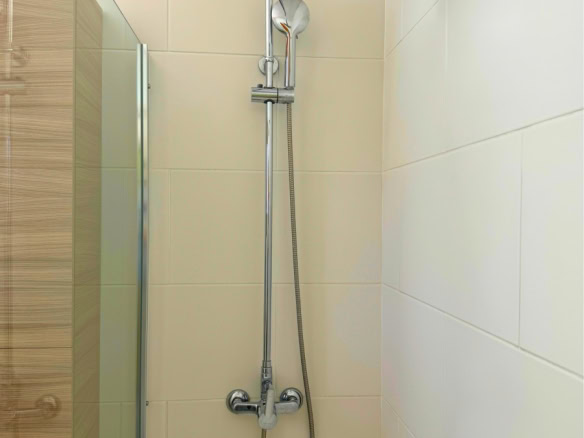 Chrome shower system with a large circular rainfall head and a handheld spray on a tiled bathroom wall