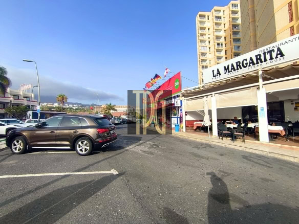 Parking lot outside La Margarita restaurant with outdoor dining under a white awning; brown SUV in foreground and tall buildings in the background.