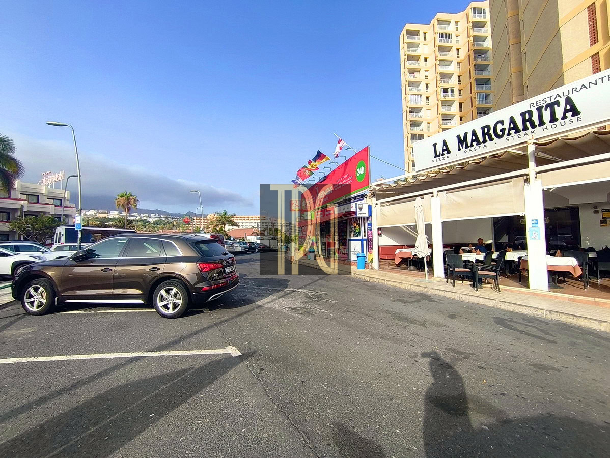 Parking lot outside La Margarita restaurant with outdoor dining under a white awning; brown SUV in foreground and tall buildings in the background.
