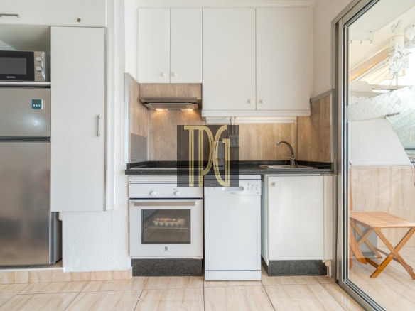 Small white kitchen with a stainless steel fridge, microwave, oven, and dishwasher along a granite counter, with a sink and white upper cabinets.