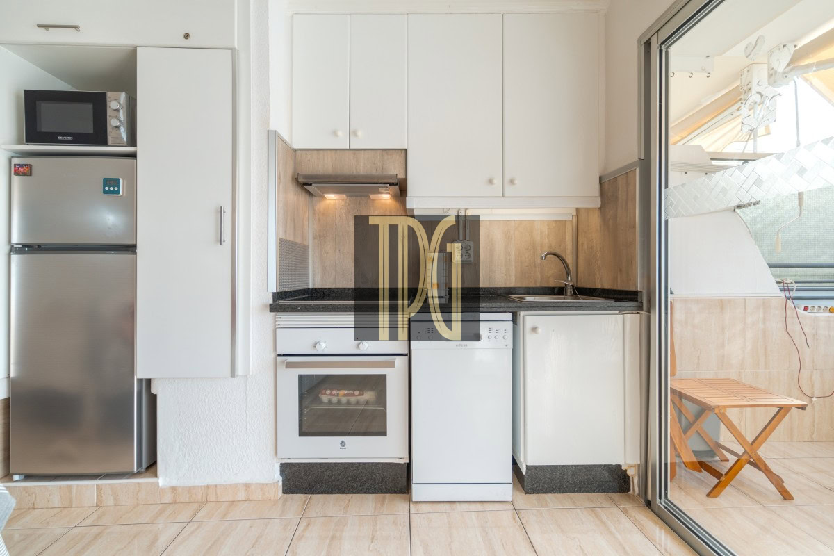 Small white kitchen with a stainless steel fridge, microwave, oven, and dishwasher along a granite counter, with a sink and white upper cabinets.