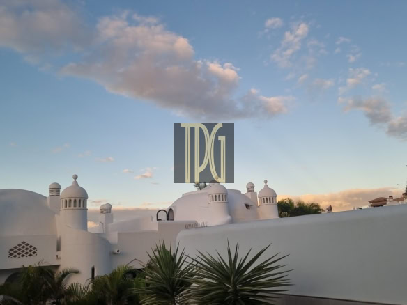 White domed buildings with palm plants against a blue sky; a TDG watermark sits centered on the image.