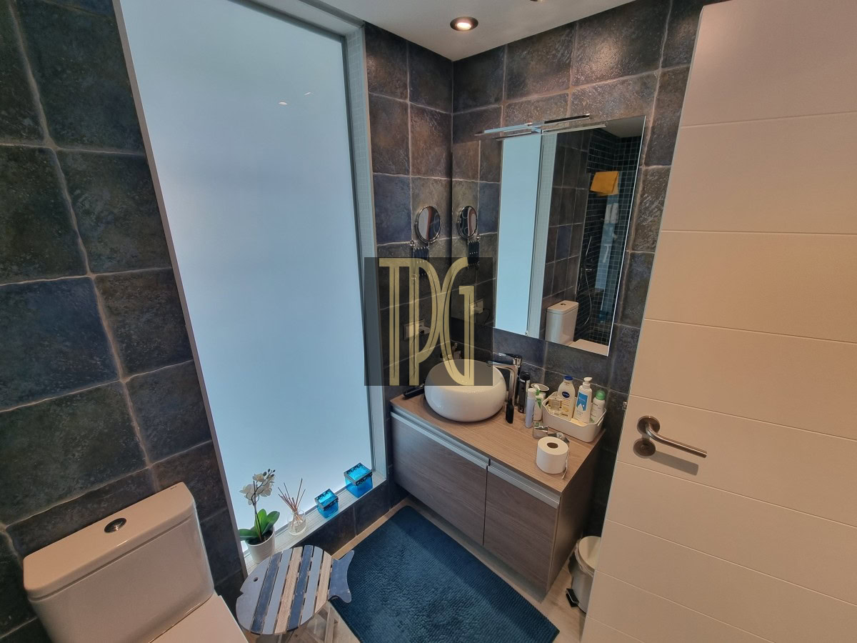 Modern bathroom with frosted tall window, slate-tiled walls, white toilet, and a wooden vanity with a round vessel sink and mirror.