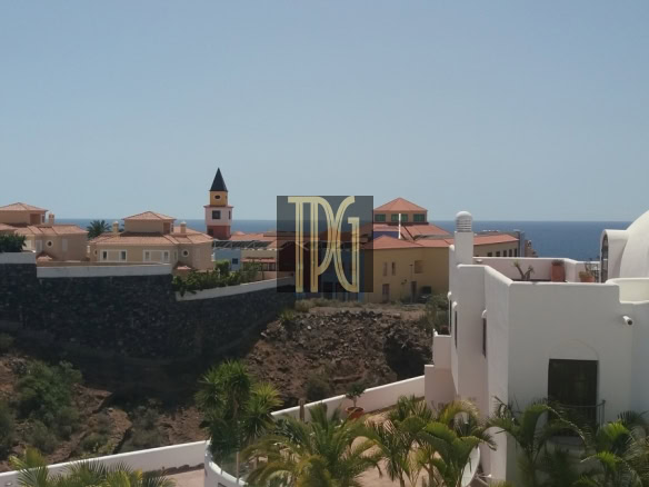 Coastal Mediterranean village with white domed buildings and terracotta roofs overlooking the blue sea.