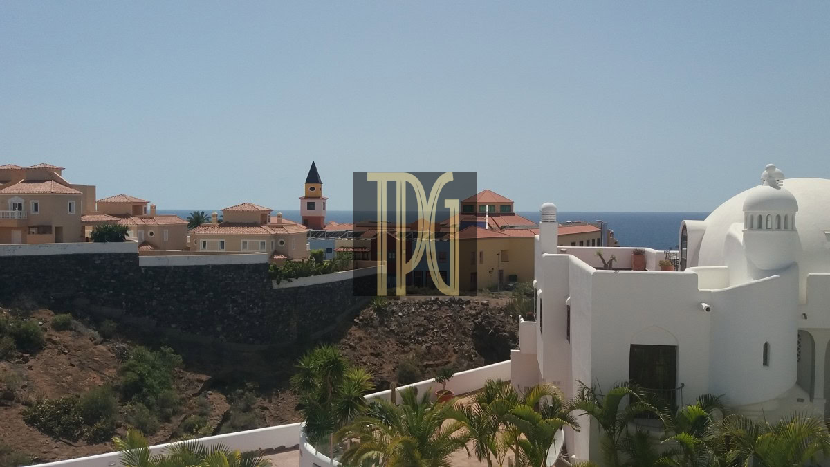 Coastal Mediterranean village with white domed buildings and terracotta roofs overlooking the blue sea.