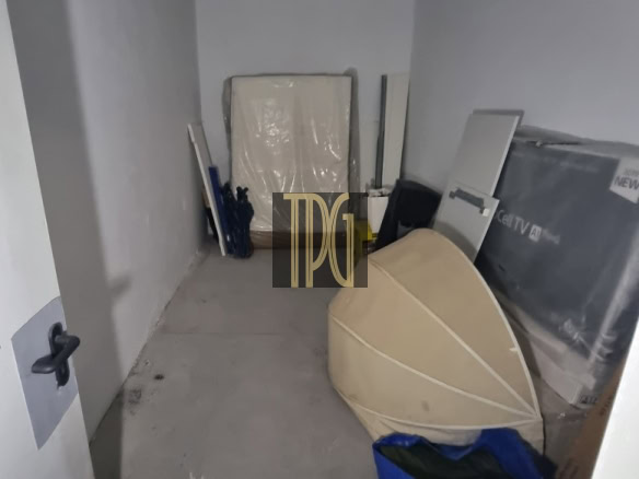 Small cluttered storage room with a large rounded object leaning against the wall and a blue bag in the foreground