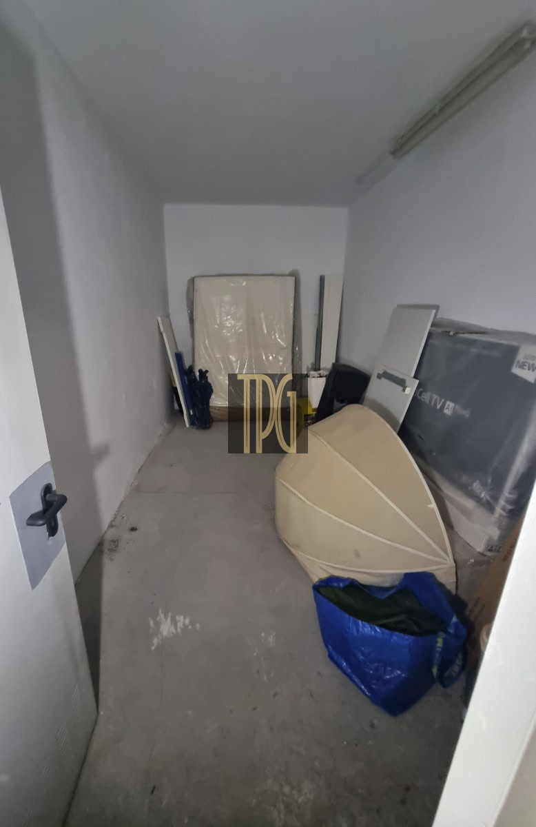 Small cluttered storage room with a large rounded object leaning against the wall and a blue bag in the foreground