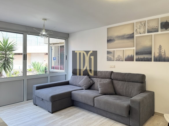L-shaped gray sofa in a bright living room with a multi-panel nature art wall and large front windows letting in daylight.