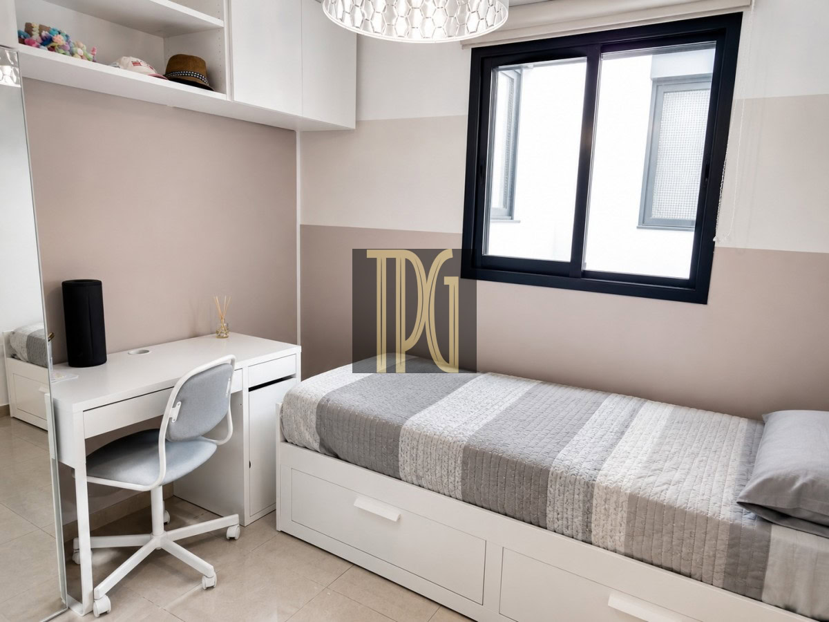 Unknown-4 Small white bedroom with a single bed, desk, chair, and built-in storage under a window.