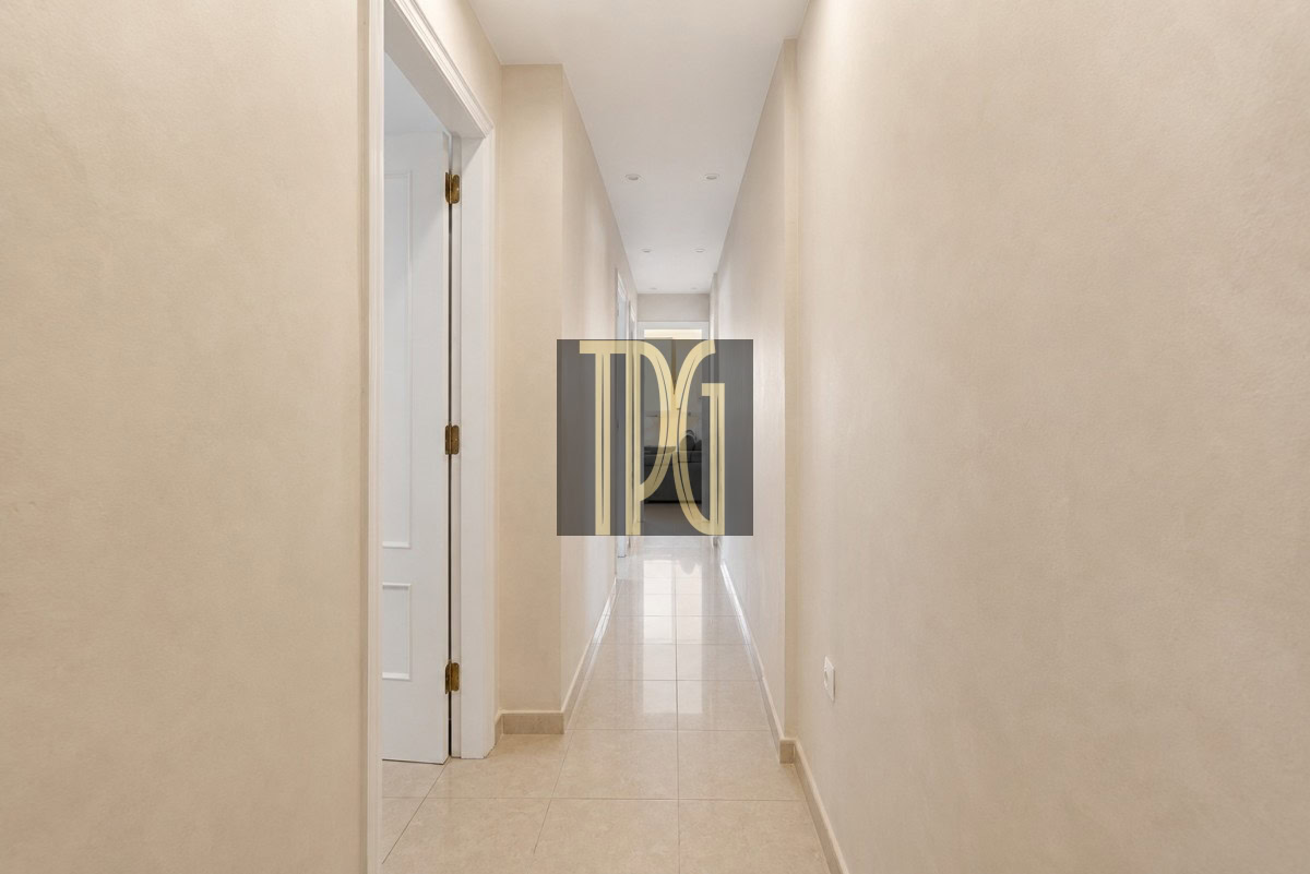 Unknown Long beige hallway with tiled floor and white doors, leading to a bright end.